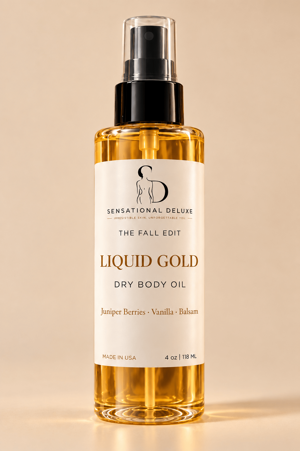 A 4 oz bottle of Sensational Deluxe 'The Fall Edit' Liquid Gold Dry Body Oil, featuring a clear bottle filled with golden oil, a black spray pump, and a cream-colored label, set against a warm beige background.